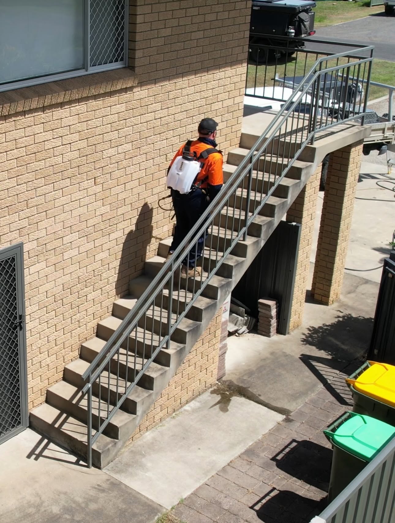 Danny applying pest treatment beside an external staircase
